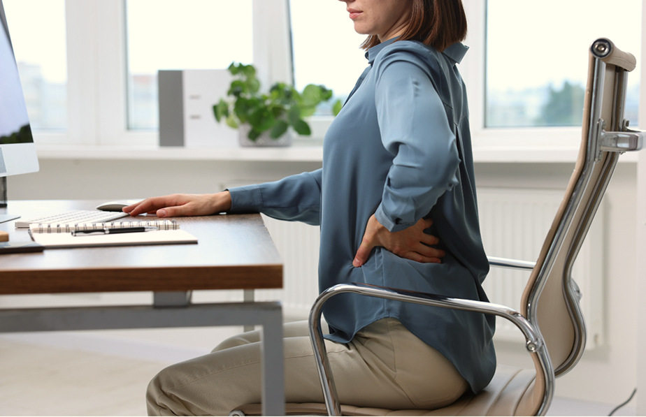 Une femme assises à un bureau qui semble avoir mal au dos